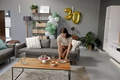 Woman arranging snacks on table in living room for 30th birthday celebration - PhotoDune Item for Sale