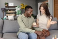 Smiling couple exchanging gifts on couch during celebration at home - PhotoDune Item for Sale