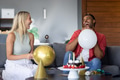 Friends laughing and enjoying balloons at home during festive celebration - PhotoDune Item for Sale