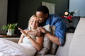 African American man hugging smiling woman on couch at home, enjoying togetherness - PhotoDune Item for Sale