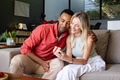 Smiling couple exchanging gift on sofa, enjoying joyful moment together - PhotoDune Item for Sale
