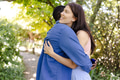 Couple embracing in garden, woman smiling joyfully while holding engagement ring box - PhotoDune Item for Sale