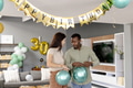 Couple decorating living room with balloons for birthday celebration at home - PhotoDune Item for Sale