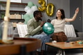 Celebrating 30th birthday, friends decorating with balloons and smiling in living room - PhotoDune Item for Sale
