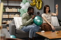 Friends preparing for birthday party, inflating balloons and decorating living room - PhotoDune Item for Sale