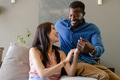 Couple laughing and holding hands on couch, enjoying quality time together - PhotoDune Item for Sale