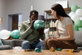 Man inflating balloon while woman smiling on couch during festive preparation - PhotoDune Item for Sale