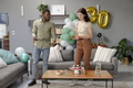Friends enjoying birthday celebration with cake and balloons in cozy living room - PhotoDune Item for Sale