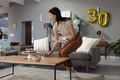 Woman preparing table with cake and snacks for birthday celebration at home - PhotoDune Item for Sale