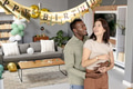 Couple celebrating birthday at home, smiling and enjoying festive decorations - PhotoDune Item for Sale