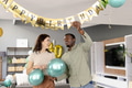 Decorating living room with balloons and banner, friends celebrating birthday joyfully - PhotoDune Item for Sale