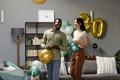 Couple celebrating birthday at home, holding balloons and smiling joyfully - PhotoDune Item for Sale