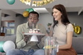 Man blowing out candles on birthday cake while woman smiling beside him - PhotoDune Item for Sale