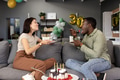 Friends laughing and sharing birthday cake together on living room sofa - PhotoDune Item for Sale