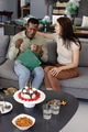 African American man opening gift with woman smiling beside him at home celebration - PhotoDune Item for Sale