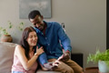 Couple sitting on couch, smiling and enjoying quality time at home together - PhotoDune Item for Sale