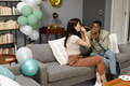 Couple celebrating at home, blowing party horns and enjoying festive balloons - PhotoDune Item for Sale