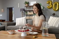 Woman celebrating birthday at home, smiling while cutting cake on table - PhotoDune Item for Sale