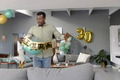 African American man decorating living room with birthday banner for celebration - PhotoDune Item for Sale