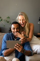 Couple sitting on couch joyfully watching tablet, sharing exciting moment together - PhotoDune Item for Sale
