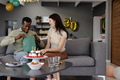 Celebrating birthday, couple exchanging gifts on sofa with cake and balloons nearby - PhotoDune Item for Sale