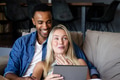 Couple relaxing on couch, smiling and watching something on tablet together - PhotoDune Item for Sale