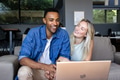 Couple smiling while watching laptop together at home, enjoying leisure time - PhotoDune Item for Sale