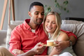 Couple celebrating birthday at home, holding cupcake with lit candle, smiling warmly - PhotoDune Item for Sale