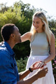 Man proposing to smiling woman in garden, holding engagement ring - PhotoDune Item for Sale