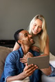 Couple enjoying time together at home, smiling while looking at tablet - PhotoDune Item for Sale