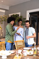 Diverse friends enjoying casual gathering with drinks and snacks at home, smiling together - PhotoDune Item for Sale