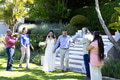 Walking hand in hand, bride and groom surrounded by joyful family outdoors - PhotoDune Item for Sale