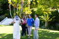 In garden, bride hugging guest while others chatting and smiling nearby - PhotoDune Item for Sale