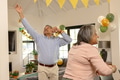 Elderly couple dancing joyfully at home during festive celebration with decorations - PhotoDune Item for Sale