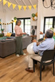 Smiling woman holding gift while man with balloons points in living room - PhotoDune Item for Sale