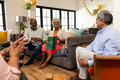 Elderly couple celebrating at home with friends, exchanging gifts and smiling warmly - PhotoDune Item for Sale