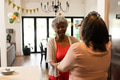 Celebrating birthday at home, African American women smiling and holding hands warmly - PhotoDune Item for Sale