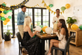 Friends celebrating birthday at home, smiling and exchanging gifts with balloons - PhotoDune Item for Sale