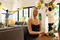 Young woman preparing decorations while friends hang birthday banner in living room - PhotoDune Item for Sale