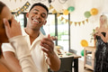 Smiling young man celebrating birthday at home with friends, enjoying moment - PhotoDune Item for Sale