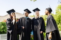 Graduates in caps and gowns celebrating together outdoors, sharing joyful moments - PhotoDune Item for Sale