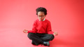 Male Elementary School Pupil Wearing Uniform Sitting And Meditating Against Red Studio Background - PhotoDune Item for Sale