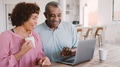 Senior Couple Sitting Around Table At Home Checking Finances On Laptop - PhotoDune Item for Sale