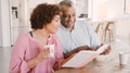 Senior Couple Sitting Around Table At Home Reading Book Together - PhotoDune Item for Sale
