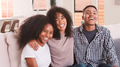 Portrait Of Smiling Adult Man And Woman With Teenage Sister Sitting On Couch At Home Together - PhotoDune Item for Sale