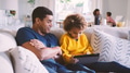 Family At Home With Father And Daughter Using Digital Tablet In Foreground - PhotoDune Item for Sale