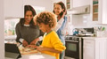 Female Multi Generation Family Prepare Meal In Kitchen Following Recipe On Digital Tablet Together - PhotoDune Item for Sale