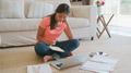 Young Girl Sitting On Floor in Lounge At Home Doing Homework Using Laptop - PhotoDune Item for Sale