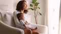 Mother Sitting On Chair In Bedroom Holding Smiling Baby Son - PhotoDune Item for Sale
