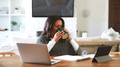 Mature Woman With Hot Drink Sitting At Table At Home Checking Finances On Laptop - PhotoDune Item for Sale
